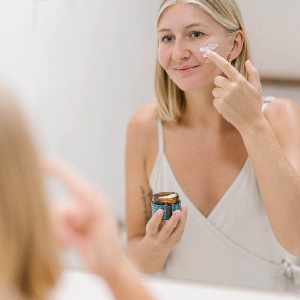 Een vrouw brengt crème aan op haar gezicht - Pro-Age Glow Set voor Rijpere Huid