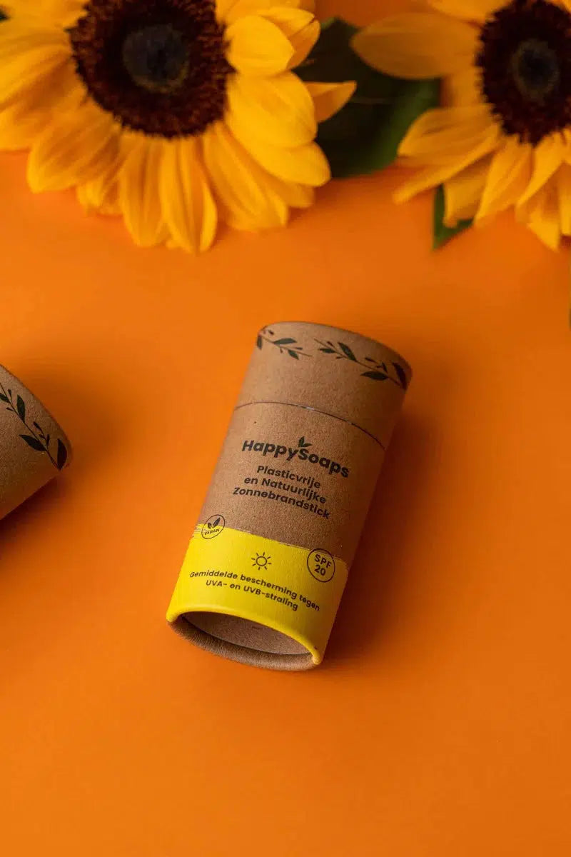 Minerale Zonnebrandstick - Sunny Citrus - SPF 20: Een gele bloem naast een tube zeep, perfect voor milieuvriendelijke bescherming tegen de zon.